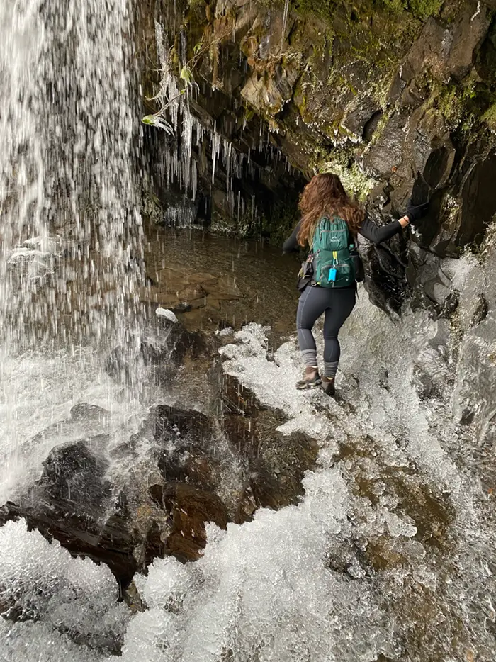 A hiker walking underneath Grotto Falls Grotto Falls (Trillium Gap Trail)